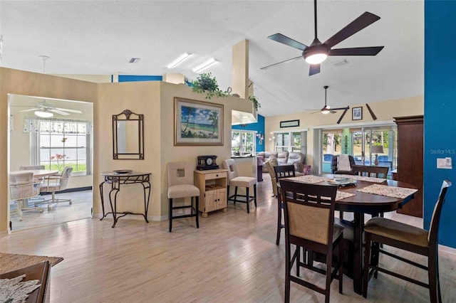 dining room featuring a textured ceiling, hardwood / wood-style flooring, ceiling fan, and lofted ceiling