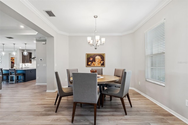 dining space featuring light wood-type flooring, an inviting chandelier, and ornamental molding