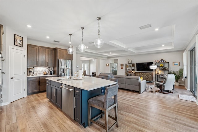 kitchen featuring sink, stainless steel appliances, an island with sink, and light hardwood / wood-style flooring