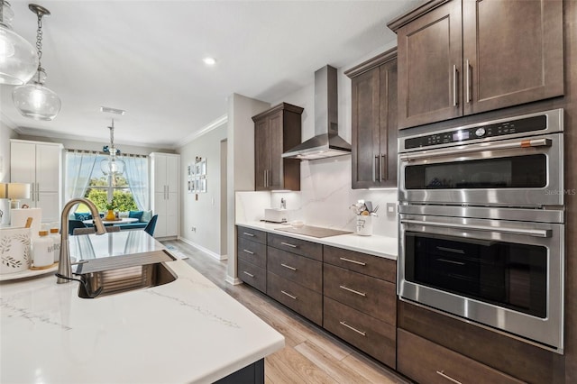 kitchen featuring ornamental molding, black electric cooktop, double oven, wall chimney range hood, and light hardwood / wood-style flooring