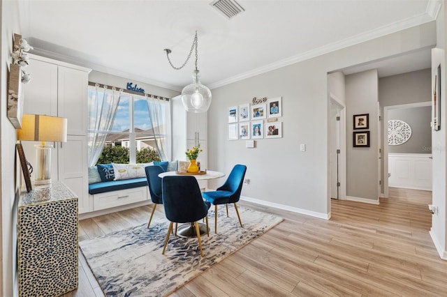 dining space with light hardwood / wood-style flooring and ornamental molding