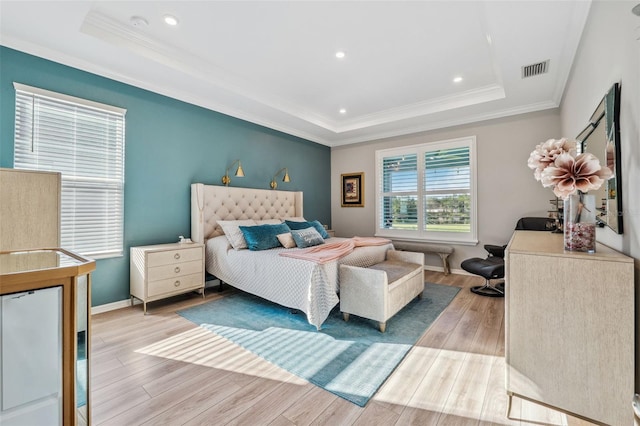 bedroom featuring ornamental molding, a tray ceiling, and light hardwood / wood-style flooring