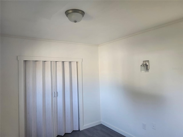 unfurnished bedroom featuring crown molding, a closet, and dark wood-type flooring