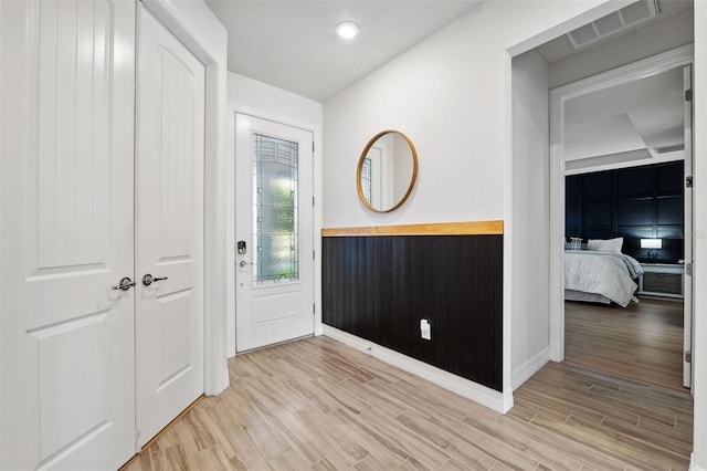 entryway with light wood-type flooring and wooden walls