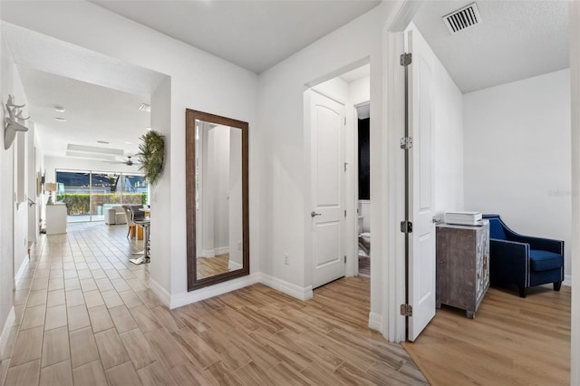 hall with light hardwood / wood-style flooring and a textured ceiling