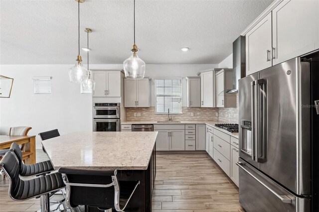 kitchen with stainless steel appliances, sink, pendant lighting, a center island, and a breakfast bar area