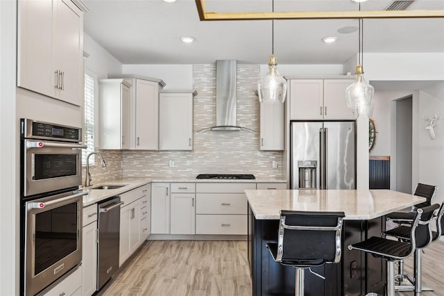 kitchen with appliances with stainless steel finishes, a kitchen breakfast bar, wall chimney range hood, pendant lighting, and a center island