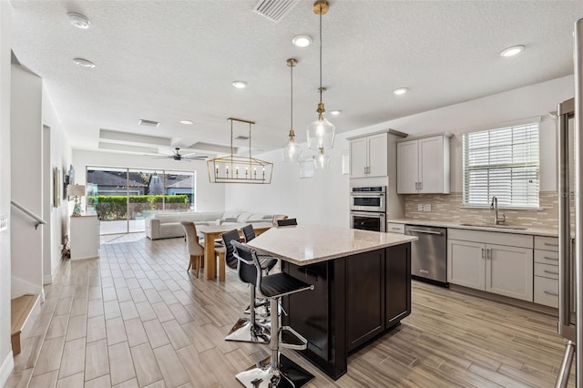 kitchen with a kitchen breakfast bar, sink, a healthy amount of sunlight, and appliances with stainless steel finishes