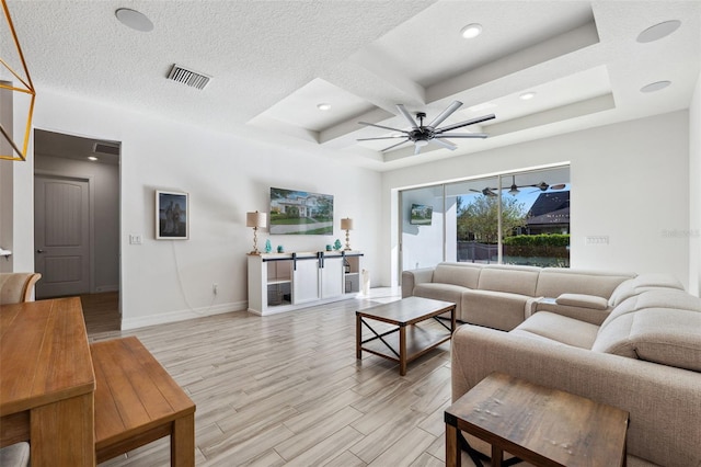 living room featuring coffered ceiling, light hardwood / wood-style flooring, ceiling fan, a textured ceiling, and a tray ceiling