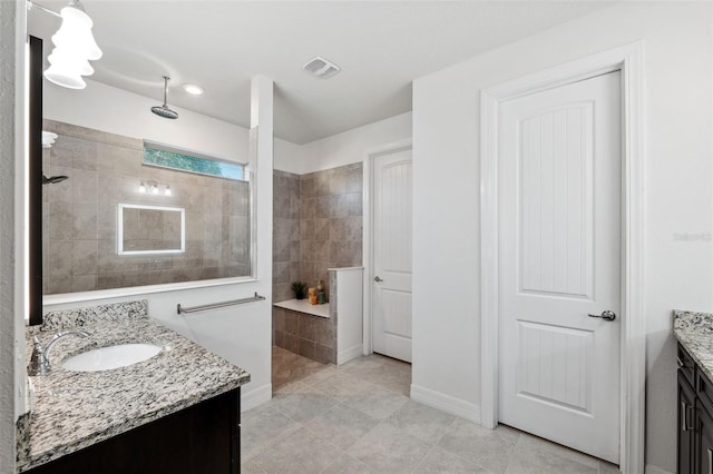 bathroom featuring tile patterned flooring, vanity, and tiled shower