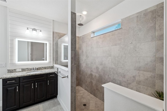 bathroom featuring a tile shower, vanity, and tile patterned floors