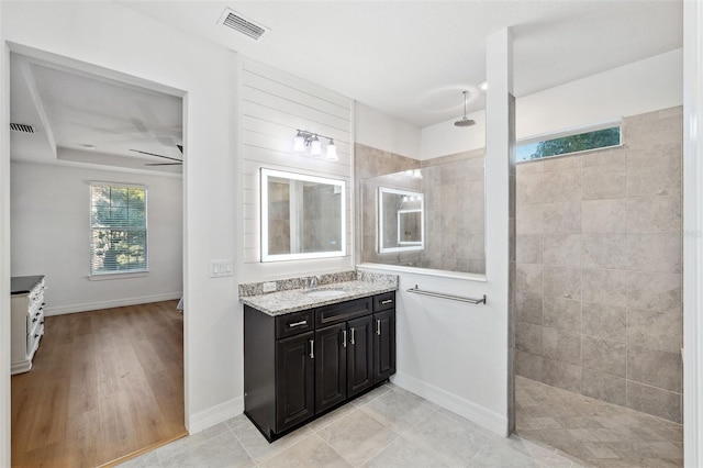 bathroom featuring tiled shower, hardwood / wood-style floors, vanity, and ceiling fan