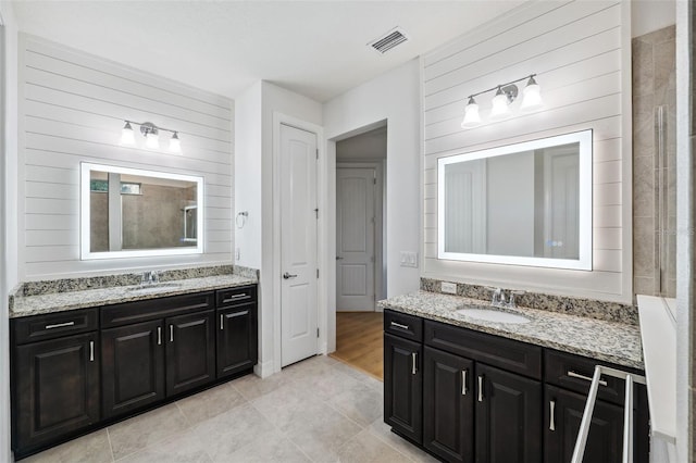 bathroom featuring tile patterned flooring, vanity, and wood walls