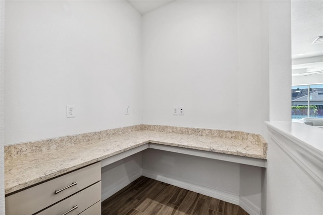 unfurnished office featuring built in desk and dark wood-type flooring