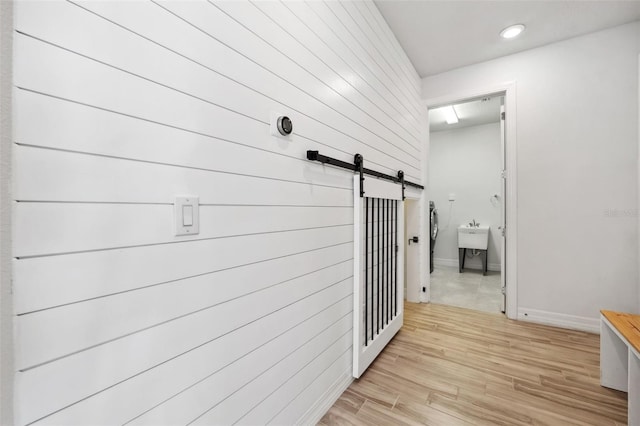 hall featuring a barn door and light hardwood / wood-style floors