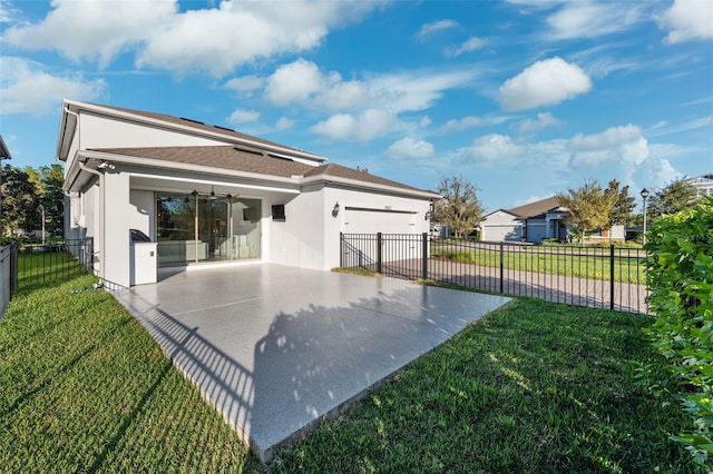 rear view of property featuring ceiling fan, a yard, and a garage