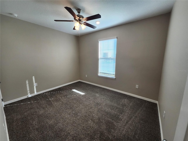 empty room featuring dark carpet and ceiling fan