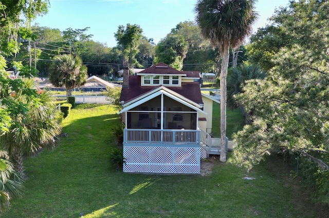 back of property with a lawn and a sunroom