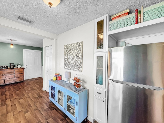 kitchen featuring white cabinets, a textured ceiling, stainless steel refrigerator, and dark wood-type flooring