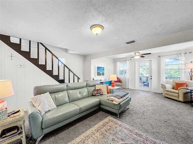 carpeted living room with a wealth of natural light, ceiling fan, and a textured ceiling