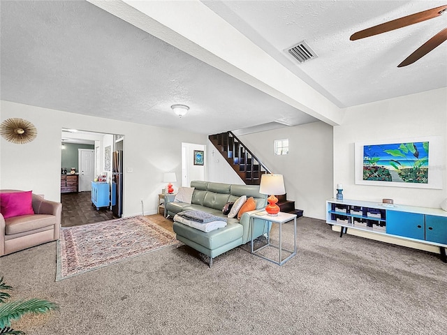 living room featuring ceiling fan, dark carpet, and a textured ceiling