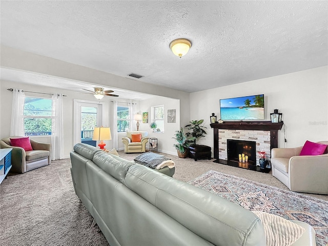 carpeted living room featuring ceiling fan, a textured ceiling, and a brick fireplace