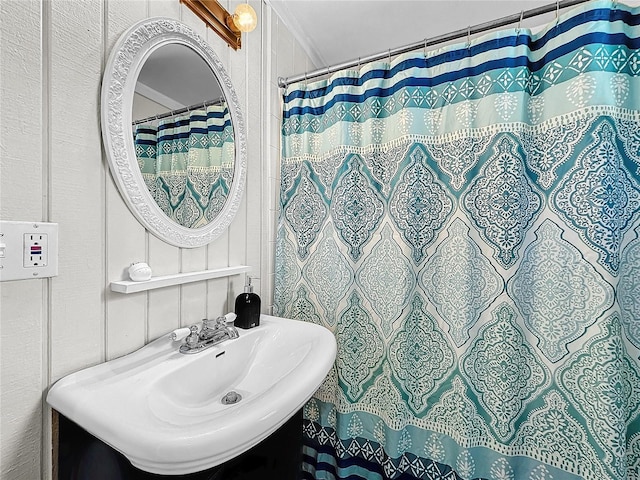 bathroom with walk in shower, crown molding, and sink