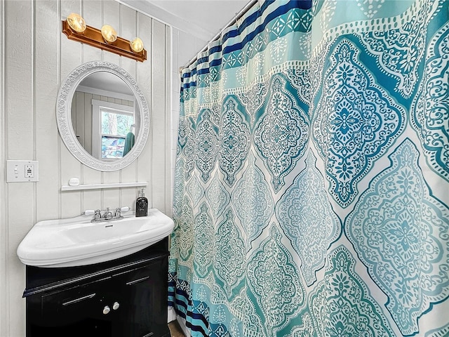 bathroom with ornamental molding, vanity, and wooden walls