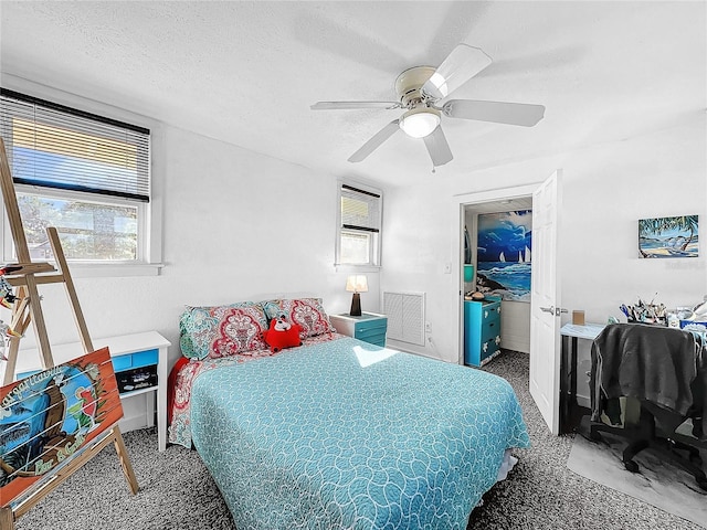 bedroom featuring ceiling fan, carpet floors, and a textured ceiling