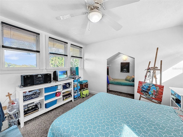 bedroom featuring ceiling fan, dark carpet, and a textured ceiling