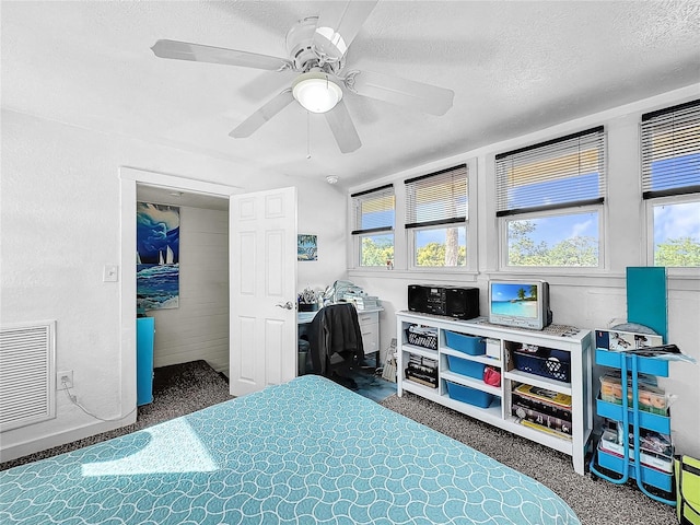 carpeted bedroom with ceiling fan and a textured ceiling