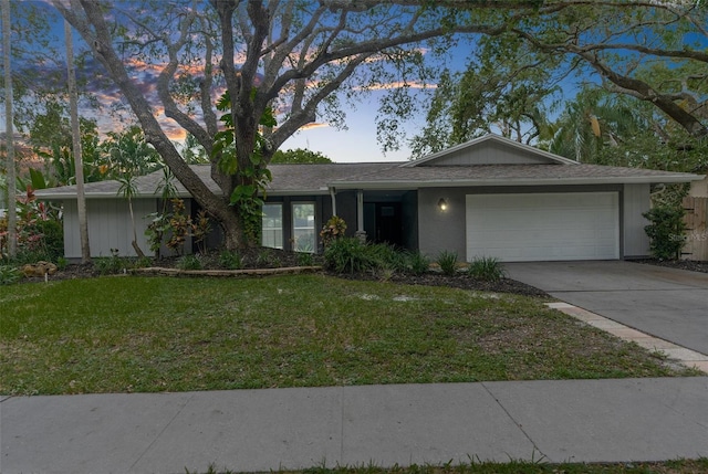 ranch-style home featuring a lawn and a garage