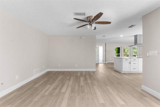 empty room featuring ceiling fan, a textured ceiling, and light wood-type flooring