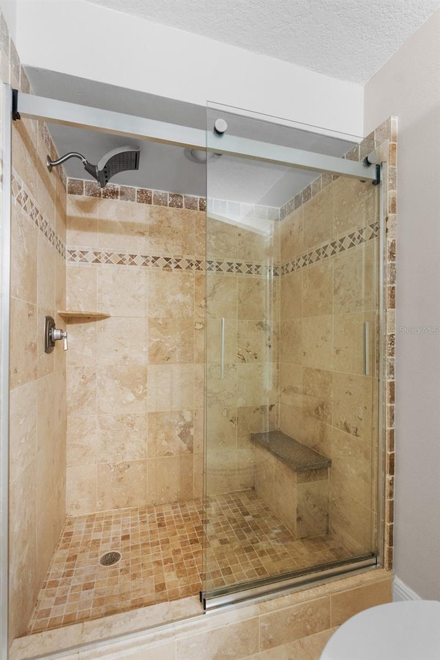 bathroom featuring toilet, a textured ceiling, and walk in shower