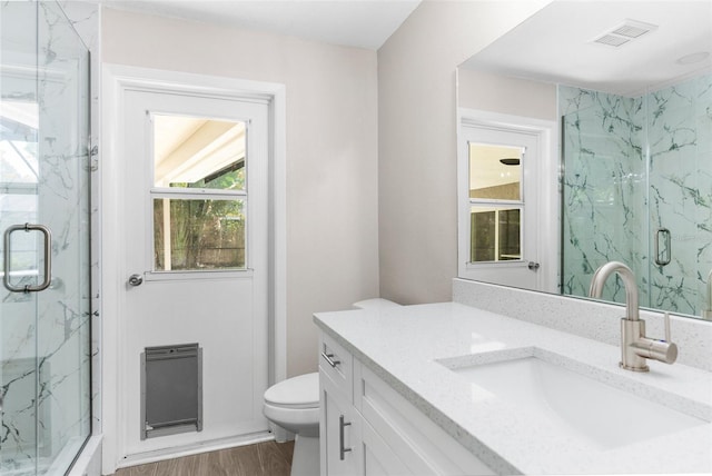 bathroom with toilet, vanity, a shower with shower door, and hardwood / wood-style flooring