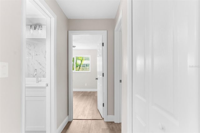 corridor with light hardwood / wood-style flooring and sink