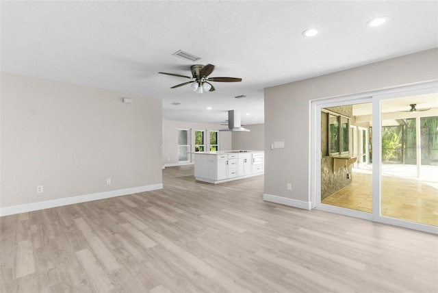 unfurnished living room featuring a textured ceiling and light hardwood / wood-style floors