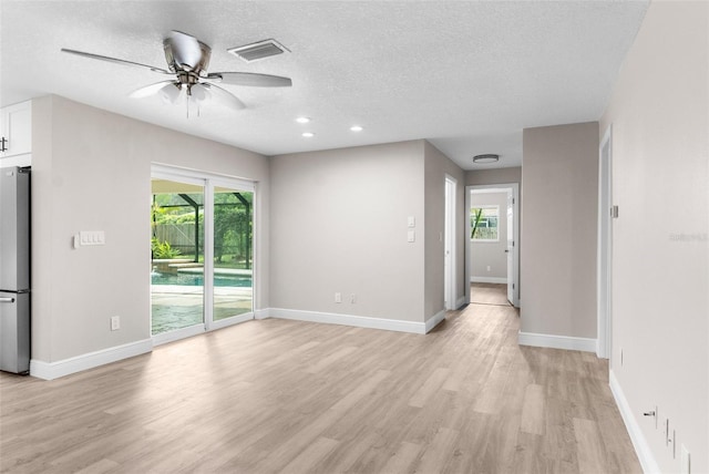 empty room featuring ceiling fan, light hardwood / wood-style floors, and a textured ceiling