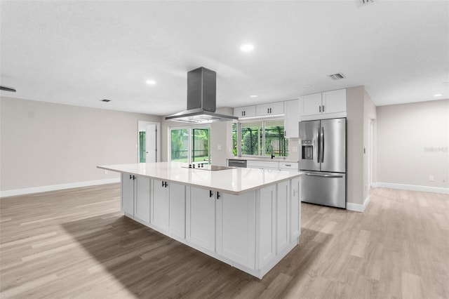 kitchen featuring white cabinets, stainless steel fridge, a kitchen island, and island range hood