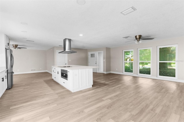 kitchen featuring white cabinets, wall chimney exhaust hood, light hardwood / wood-style floors, and appliances with stainless steel finishes