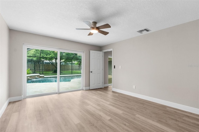 empty room with a textured ceiling, light hardwood / wood-style flooring, and ceiling fan