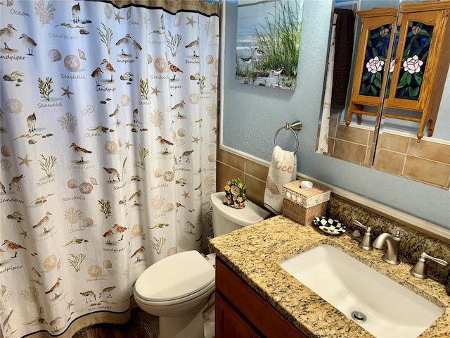 bathroom featuring toilet, decorative backsplash, and vanity