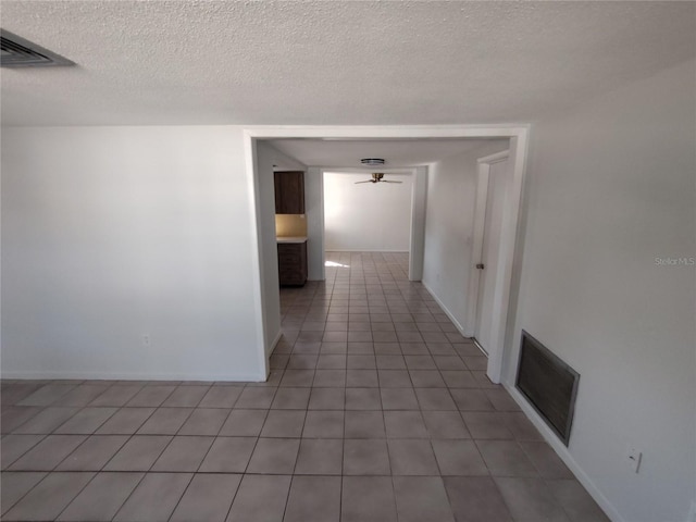 corridor featuring a textured ceiling and light tile patterned floors