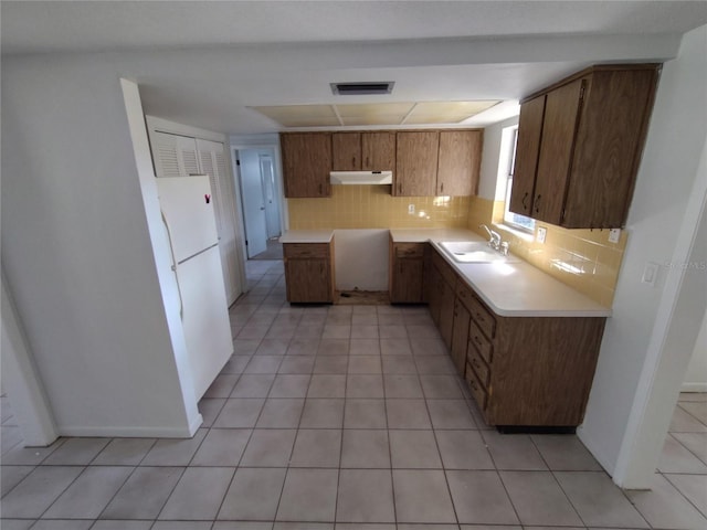 kitchen featuring sink, decorative backsplash, light tile patterned flooring, and white fridge