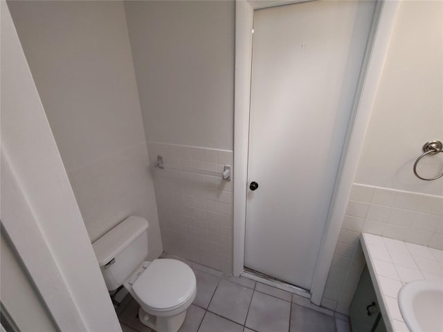 bathroom with vanity, toilet, tile patterned flooring, and tile walls