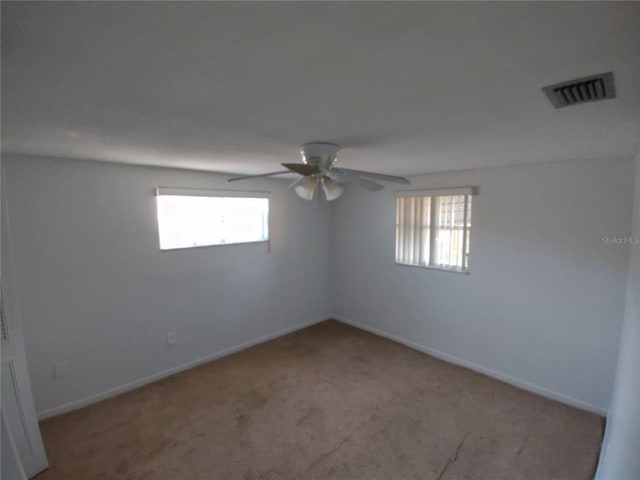 unfurnished room featuring ceiling fan, light colored carpet, and a healthy amount of sunlight