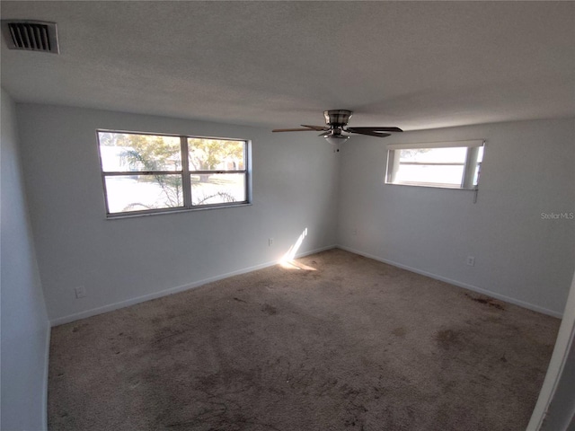 carpeted empty room featuring ceiling fan and a textured ceiling