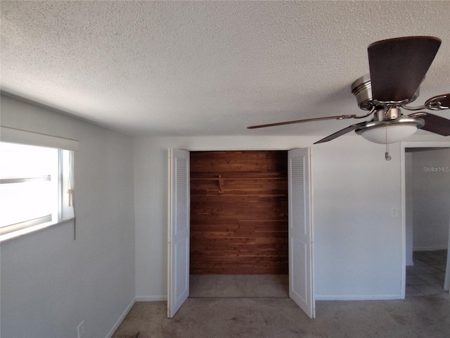 unfurnished bedroom featuring wooden walls, light colored carpet, a closet, and a textured ceiling