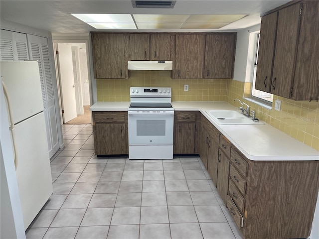 kitchen featuring range hood, light countertops, a sink, white appliances, and tasteful backsplash
