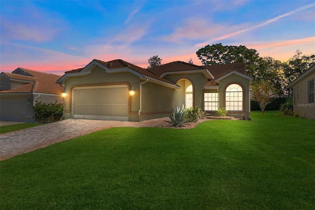 mediterranean / spanish-style house featuring a garage and a yard